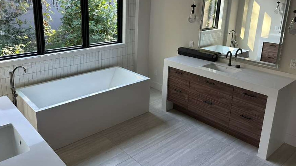 Bathroom with a walnut woodgrain slab vanity, white top and a freestanding tub