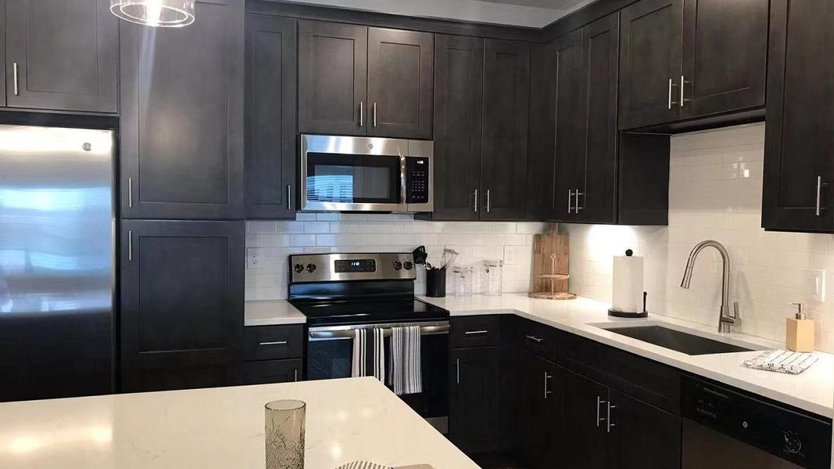 Finished kitchen with dark espresso shaker cabinets, white quartz counters, a white subway tile backsplash and stainless appliances